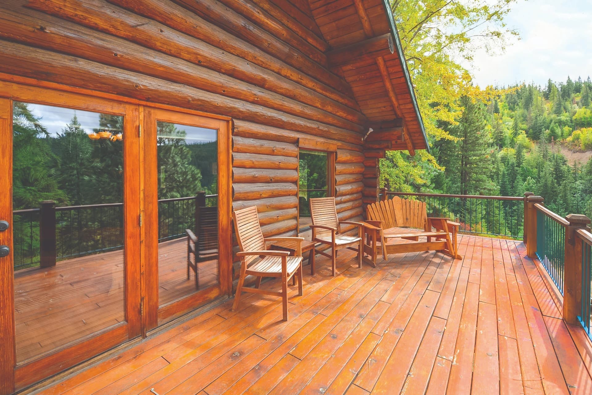 Stained wood deck on a log cabin overlooking a forest