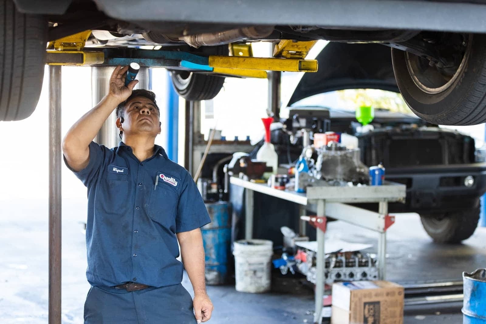 Technician working beneath a vehicle on a lift in a service bay