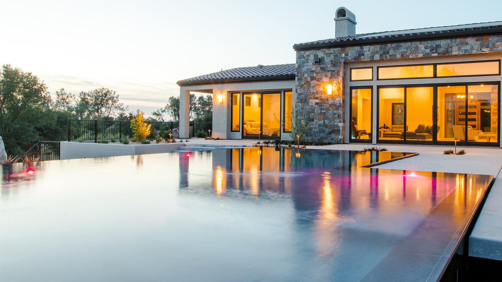 Infinity-edge pool and stone residence at dusk